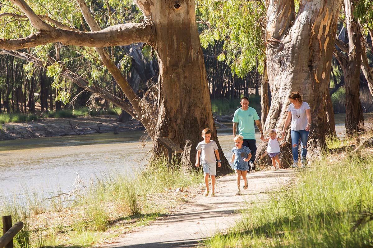 Family enjoying a relaxing walk alongside the Edward River, Deniliquin in the state's Riverina Murray region. Credit: Destination NSW