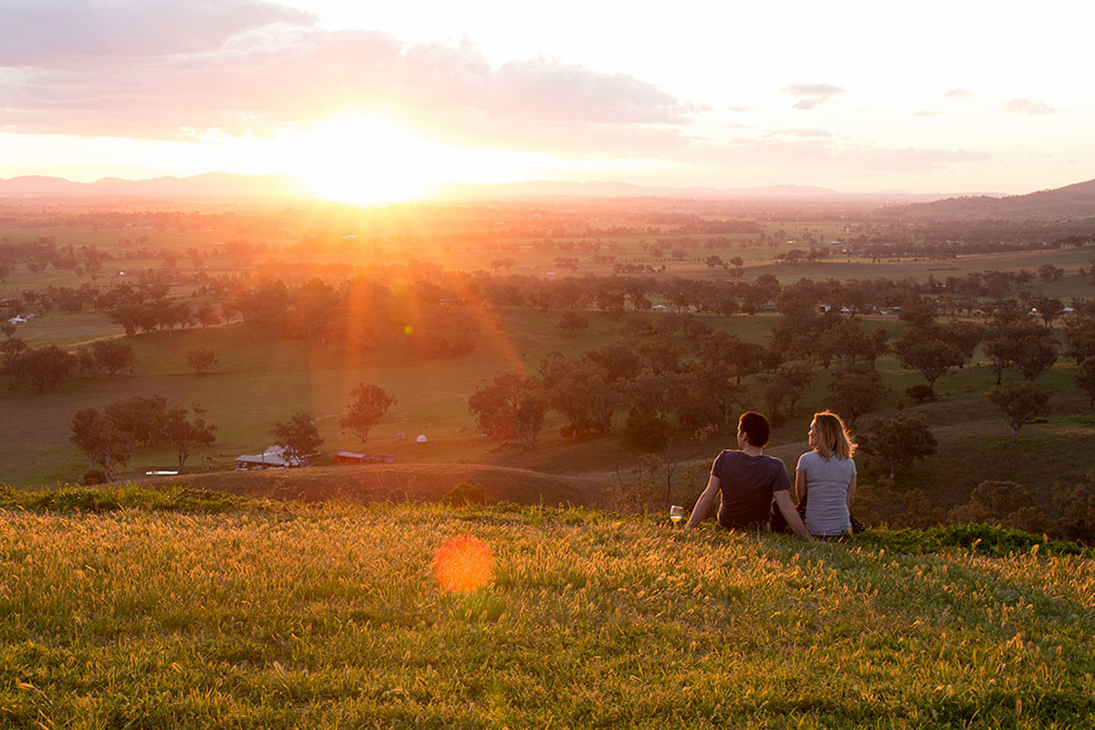 Couple enjoying a glass of wine at sunset in Tamworth's countryside. Credit: Destination NSW