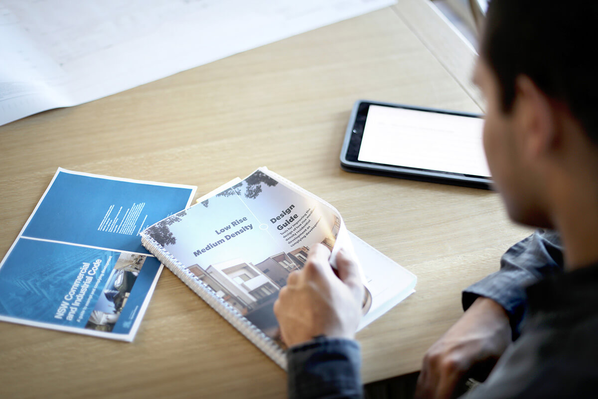 A building certifier reads a housing guideline document. Credit: NSW Department of Planning, Housing and Infrastructure / Christopher Walters